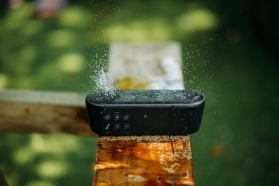 棕色木材上防水长方形黑色便携式蓝牙扬声器的选择聚焦摄影